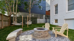 A backyard with a stone fire pit, two Adirondack chairs, and a hammock. -  White House at Grand Central (St. Louis)