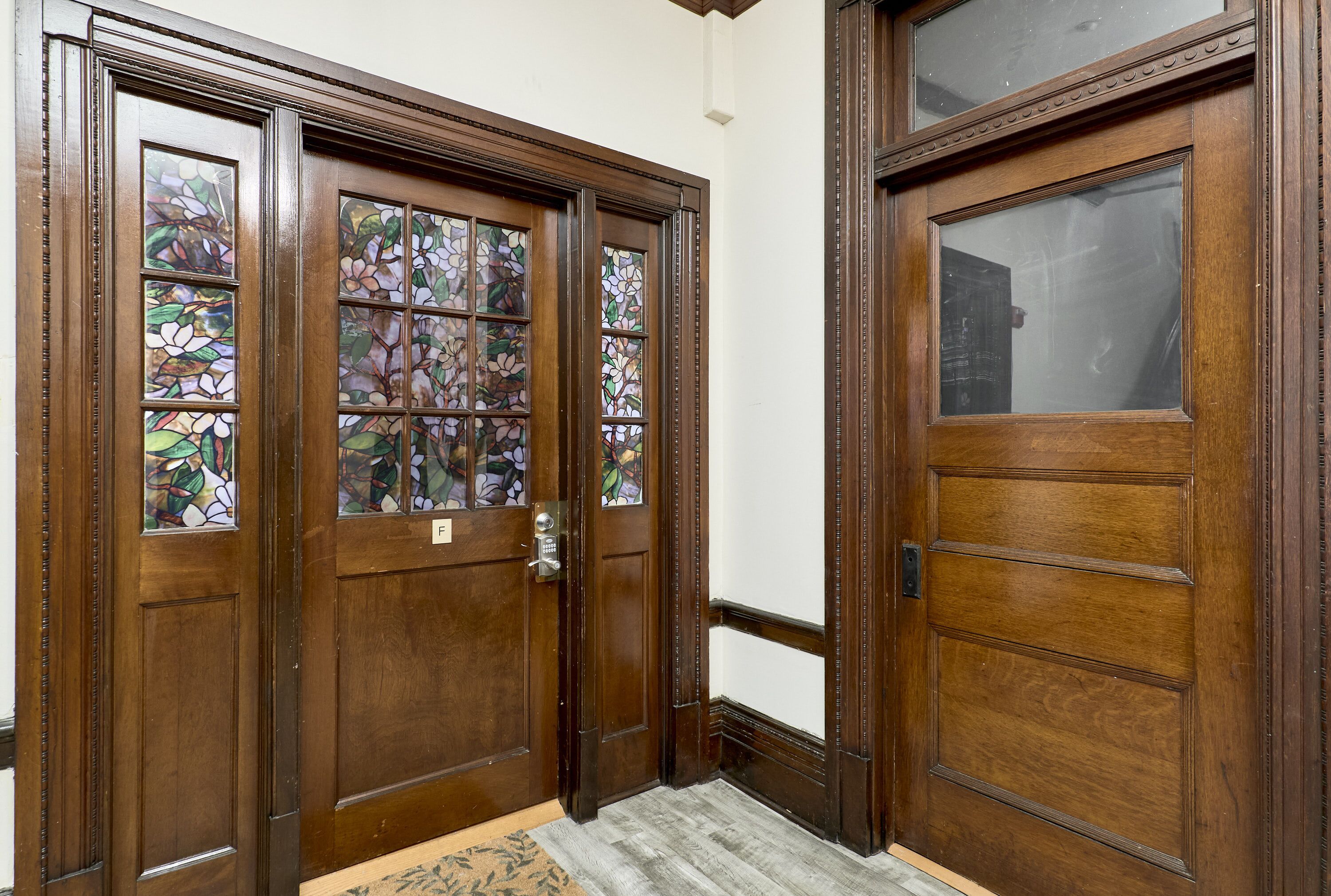 A wooden double door with stained glass panels and a doorbell.