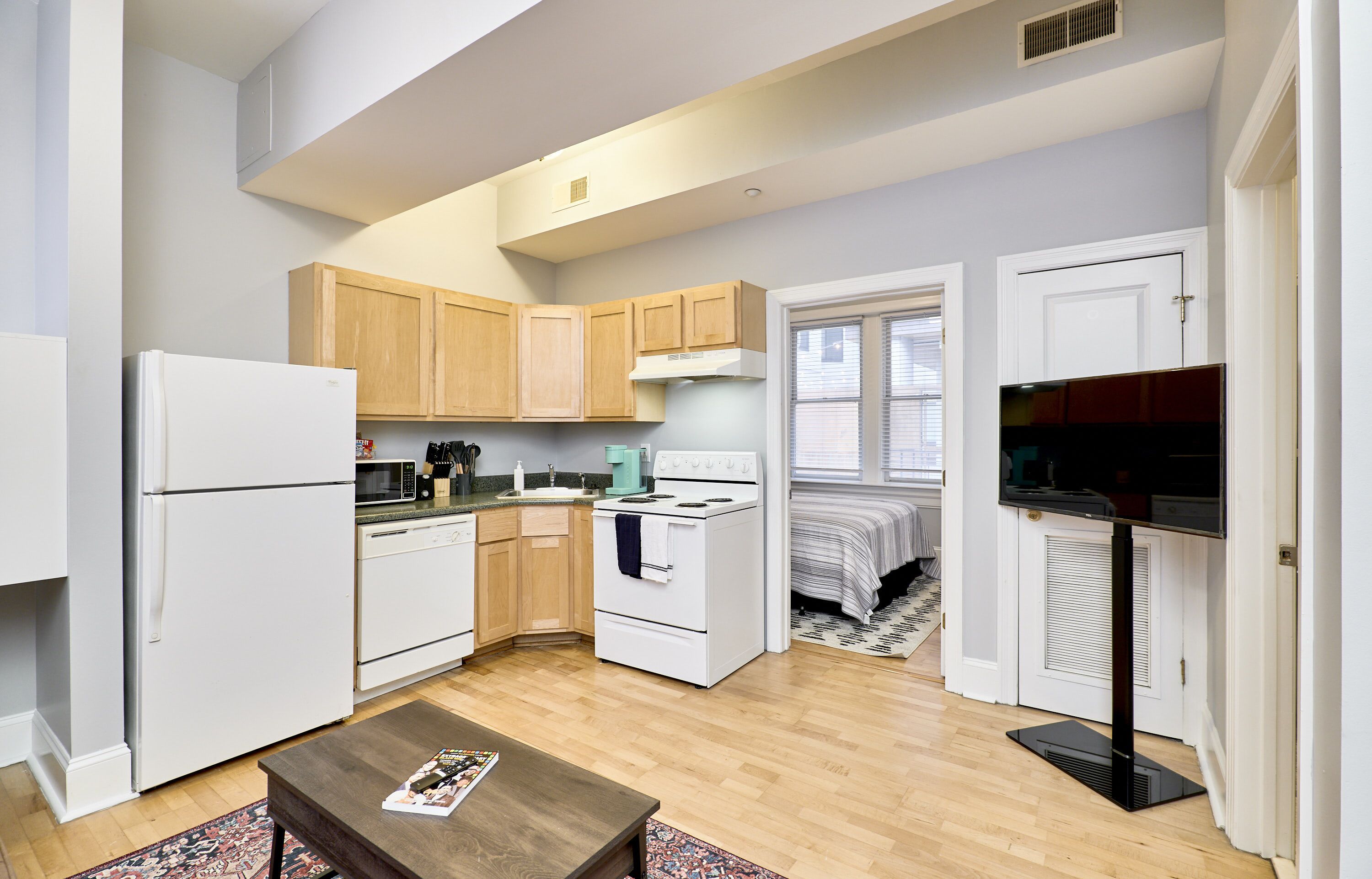 A compact kitchen with white appliances, wooden cabinets, and a small dining area.