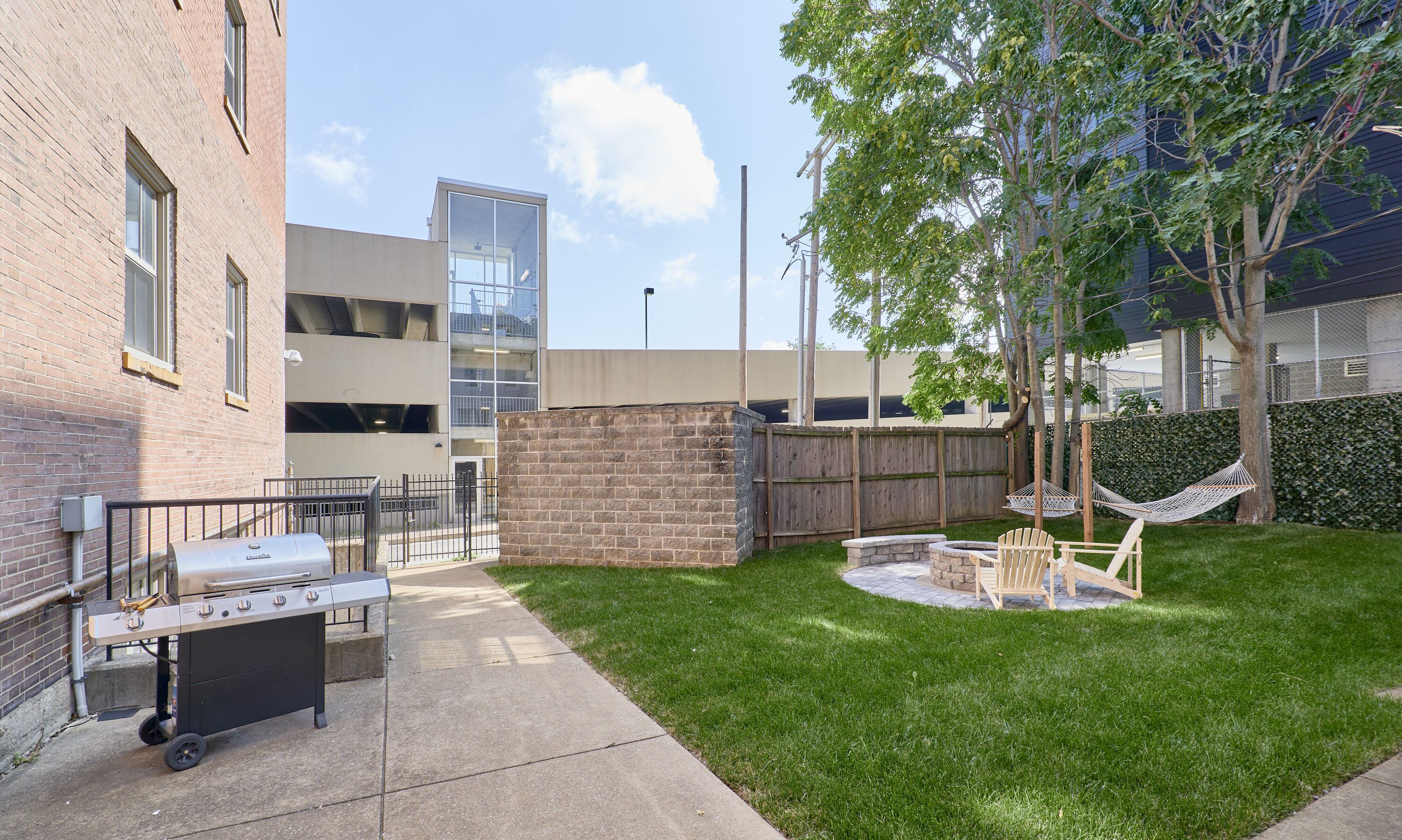 A courtyard with a barbecue grill, outdoor seating, and a hammock.