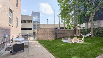 A courtyard with a barbecue grill, outdoor seating, and a hammock.