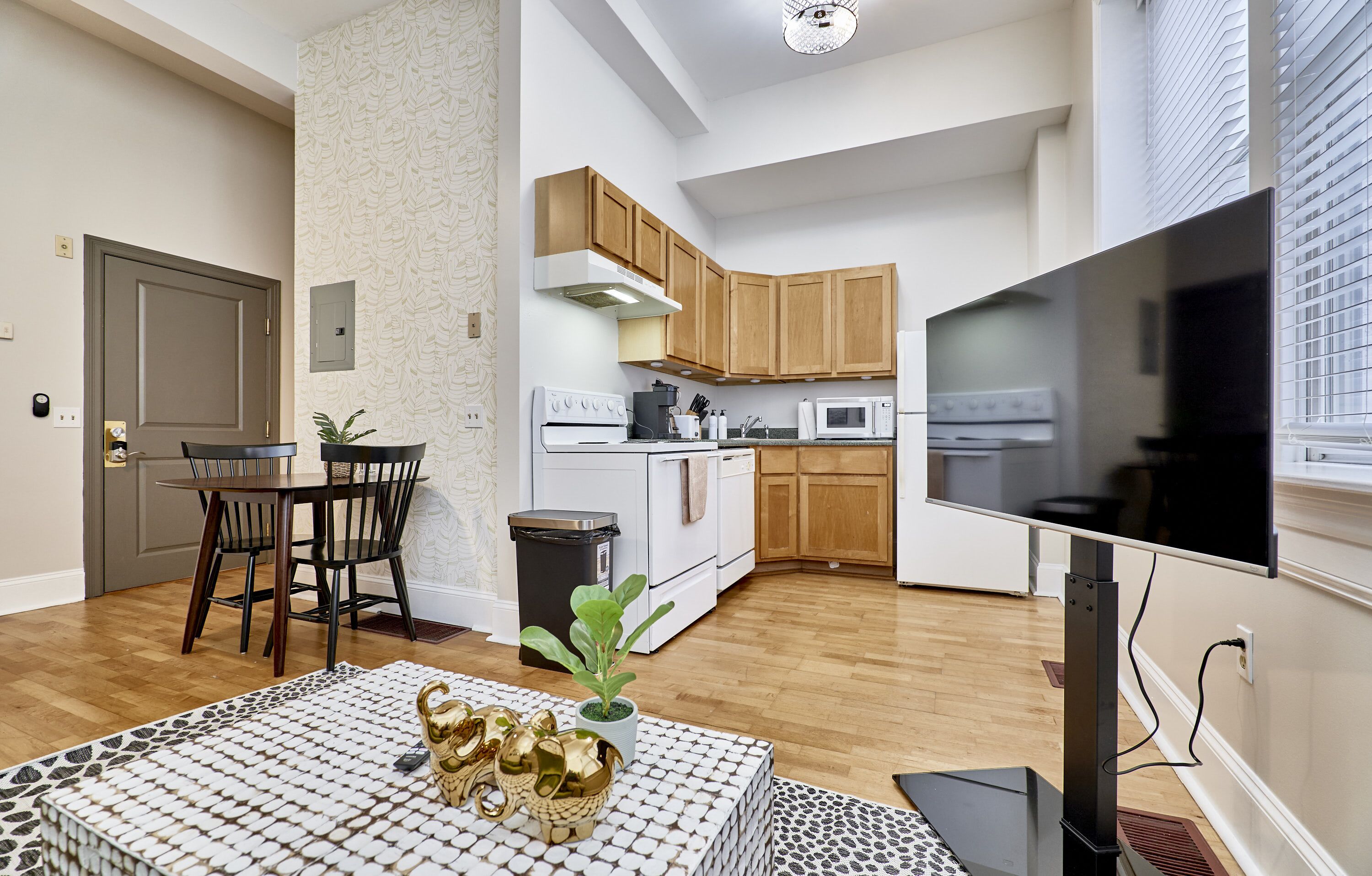 Una cocina moderna con electrodomésticos blancos, armarios de madera y una zona de comedor con mesa y sillas.