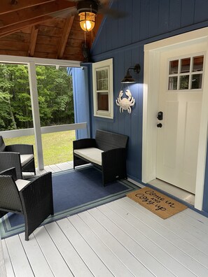 A covered porch with wicker furniture, a white door, and a welcome mat. - Cozy cottage in the Winthrop Lakes Area (Winthrop)