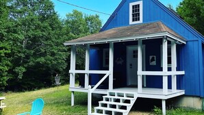 Une maison bleue avec un porche et un petit escalier menant à l’entrée.