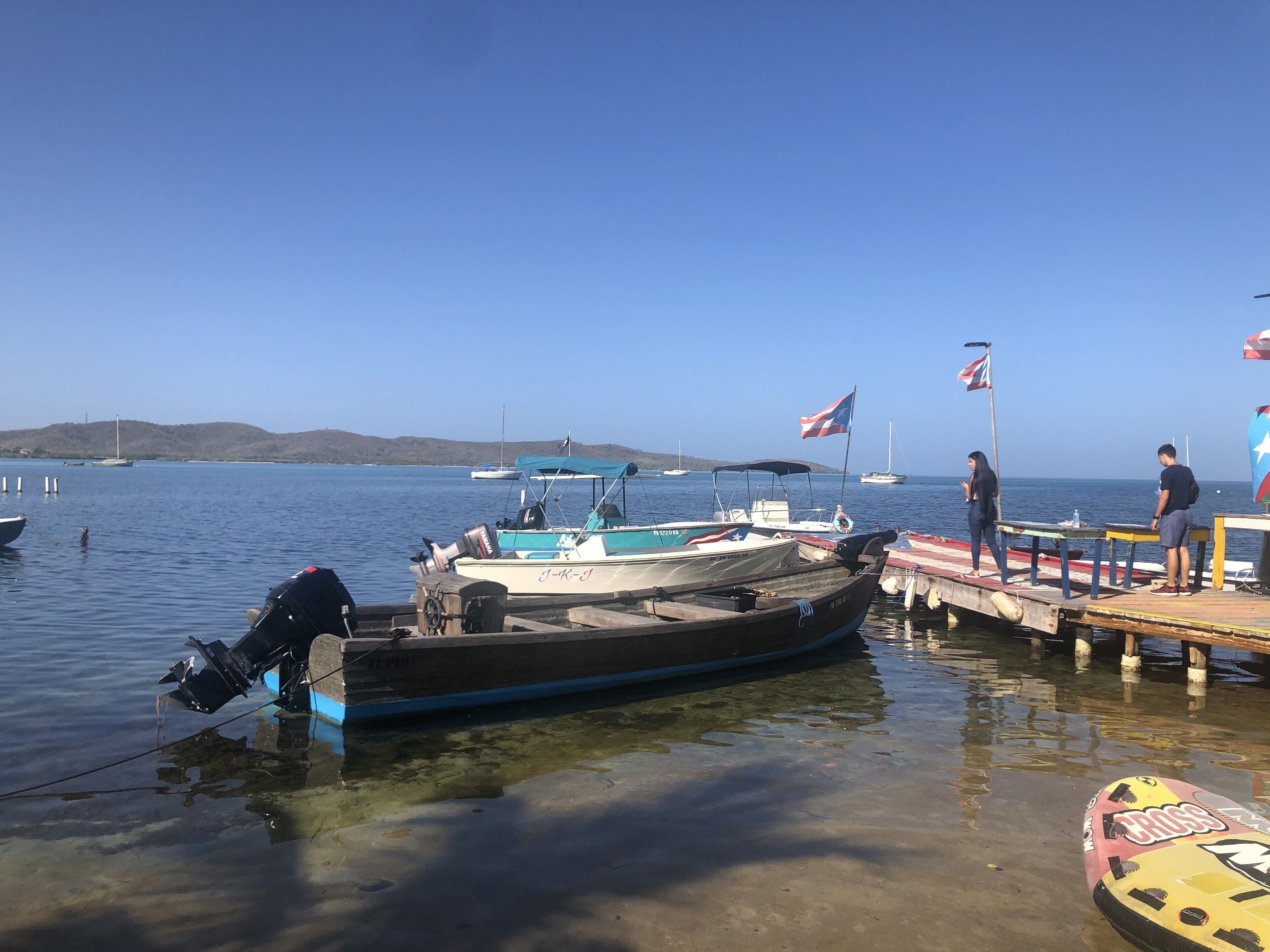 Un quai avec des bateaux, un drapeau et un ciel dégagé.