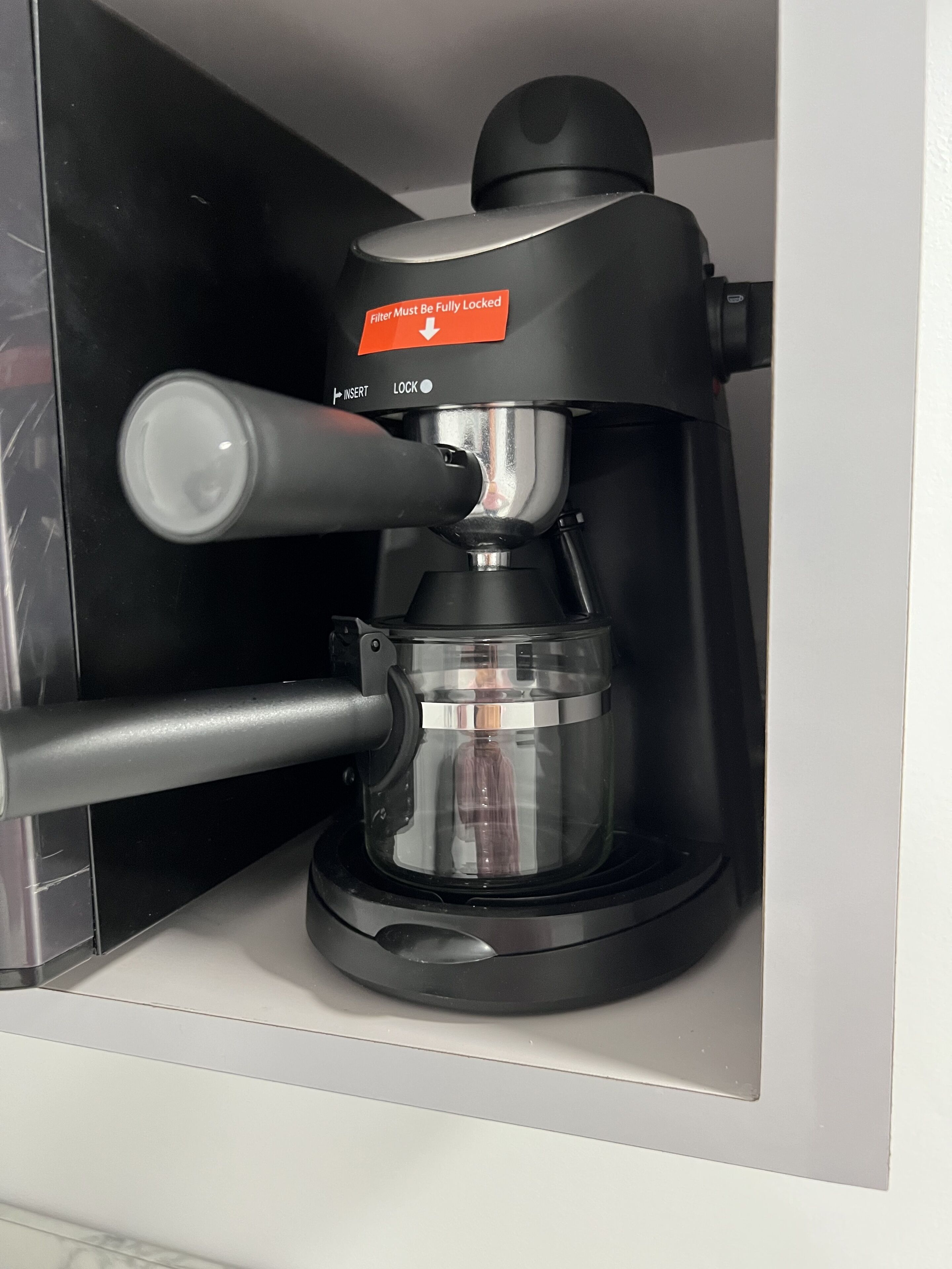 Een koffiezetapparaat met een transparant waterreservoir en een zwart lekbakje.