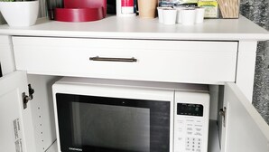 Une petite cuisine équipée d’un four à micro-ondes, d’une machine à café et d’une petite plante en pot.