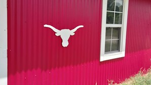 Un bâtiment rouge avec une fenêtre blanche et une silhouette blanche en forme de tête de taureau sur le mur.