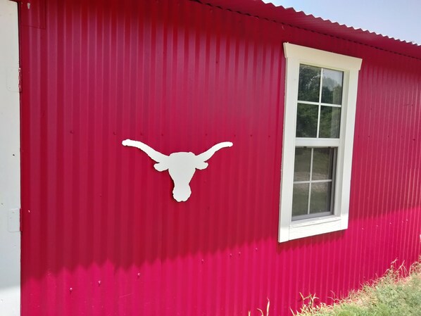 Un edificio rojo con una ventana blanca y un relieve blanco con forma de cabeza de toro en la pared.