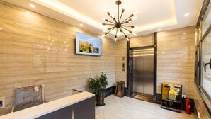 A modern reception area with a marble floor, a reception desk, a digital display, and an elevator. - Lanzhou Jinyuan Zhijia Hotel (Lanzhou)