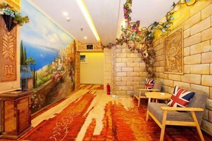 Una habitación con un mural, una pared de ladrillo, un sofá con un cojín con motivos de bandera y una alfombra estampada.