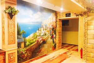 Un pasillo con un mural de una escena costera, un extintor y un cartel en la pared.