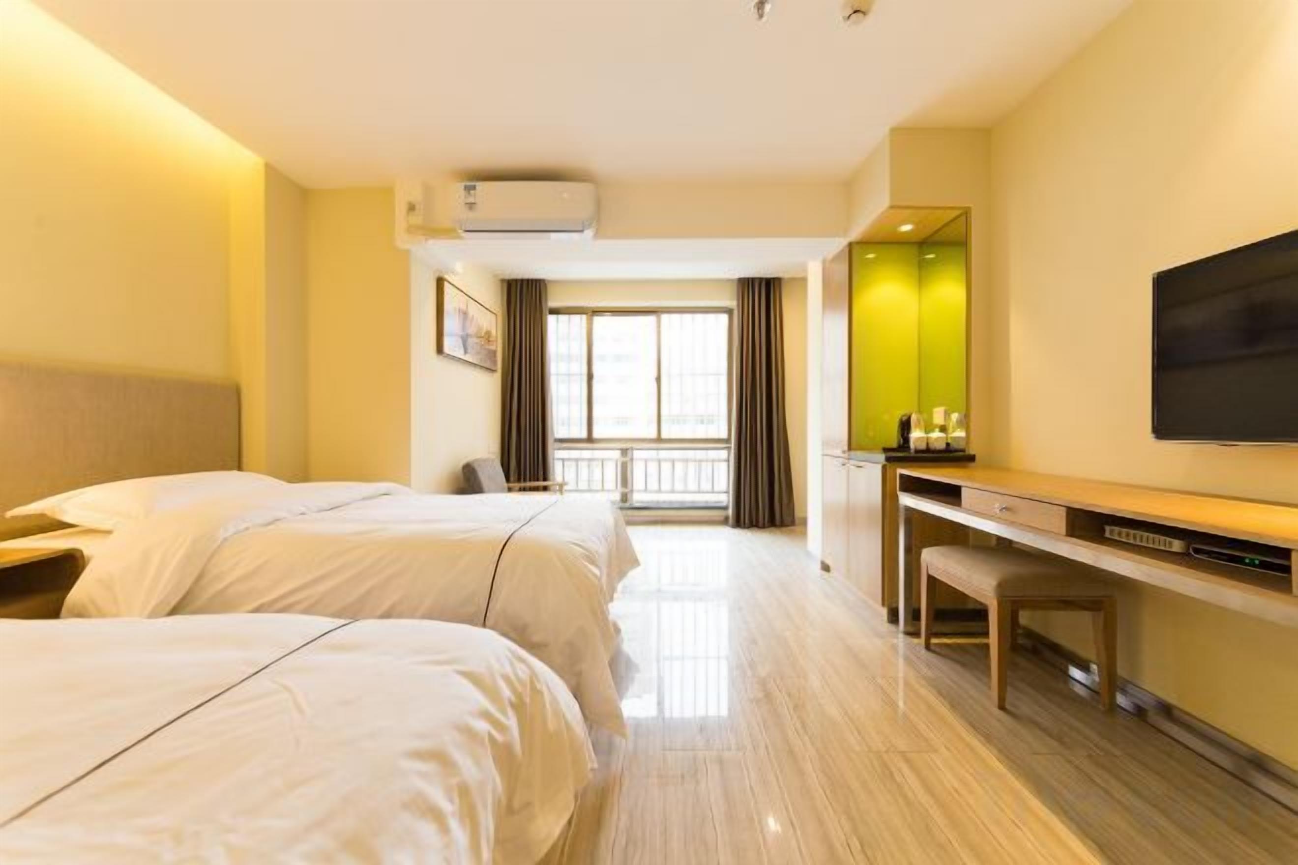 A hotel room with two beds, a desk, a chair, a TV, and a window with curtains.