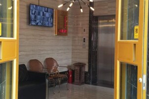 Un vestíbulo de hotel con mostrador de recepción, zona de estar y ascensor.