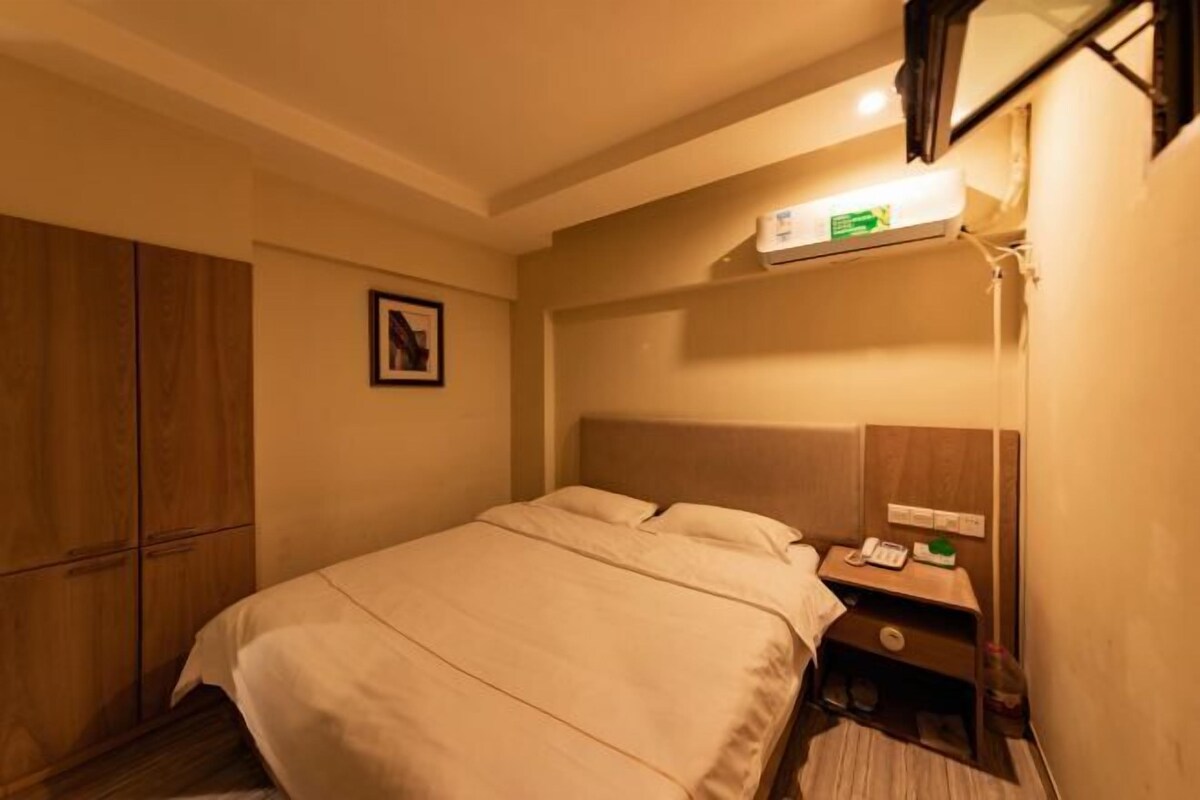 Una habitación de hotel con una cama, una mesita de noche, un teléfono y un aire acondicionado de pared.