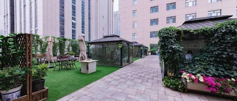 Un patio con un camino empedrado, mobiliario exterior y vegetación.