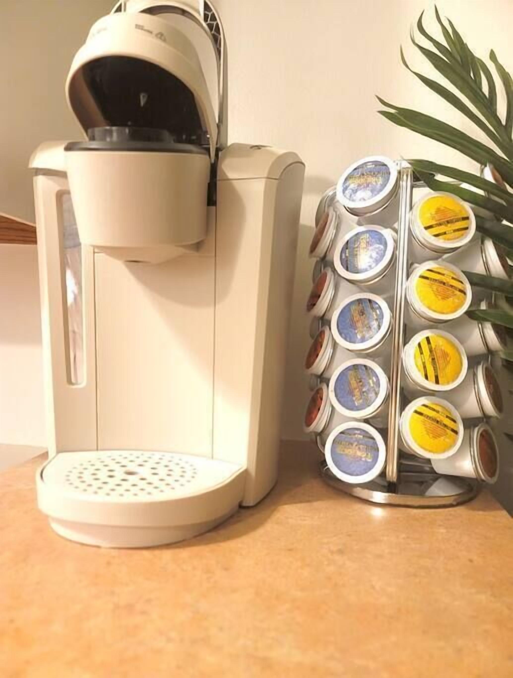 A coffee machine with a built-in grinder and a container with multiple coffee pods.