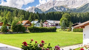 Un pueblo de montaña con casas de madera tradicionales, un césped verde y vistas a las montañas.