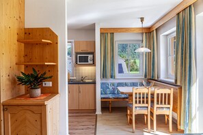 Une cuisine compacte dotée de meubles en bois, d’un four à micro-ondes, d’un évier et d’un coin repas avec un banc et des chaises.