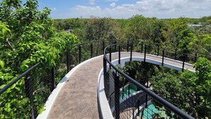 A curved pathway with a metal railing, surrounded by lush greenery and trees, leading to a viewing platform. - CASA MEXICANA MODERNA - PISCINA PRIVADA (Tulum)