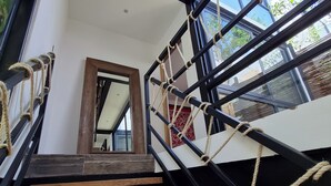 A modern staircase with wooden steps and black metal railings, leading to a room with large windows and a view of greenery outside. - CASA MEXICANA MODERNA - PISCINA PRIVADA (Tulum)