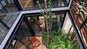 A modern interior with a glass ceiling, wooden flooring, and a seating area with chairs and a table. - CASA MEXICANA MODERNA - PISCINA PRIVADA (Tulum)