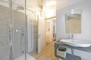 A modern bathroom with a glass shower enclosure, a white sink with a mirror, and a wooden floor. - Arco Rocks 3, Arco, Italy (Arco)