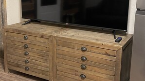 A wooden chest of drawers with a flat-screen TV mounted above it.