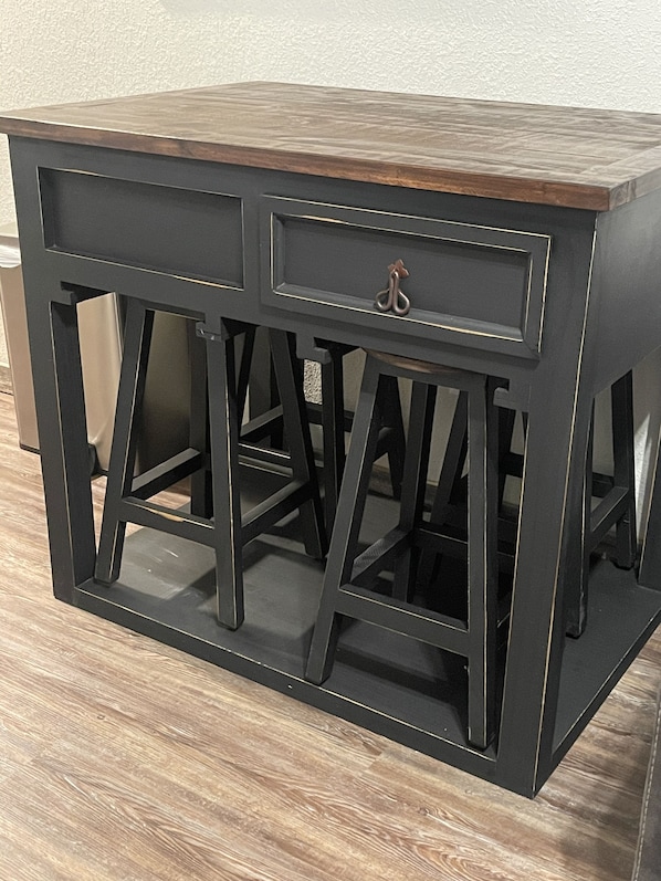 Una mesa de metal negro con tapa de madera y un cajón, con un tirador de metal.