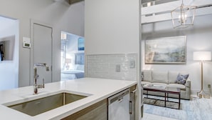 A modern kitchen with a large sink, white backsplash, and a dishwasher. - Modern Interior, Heated Pool Access (Savannah)