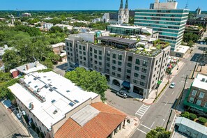 An urban building with multiple floors, a rooftop garden, and a church in the background. - Modern Interior, Heated Pool Access (Savannah)