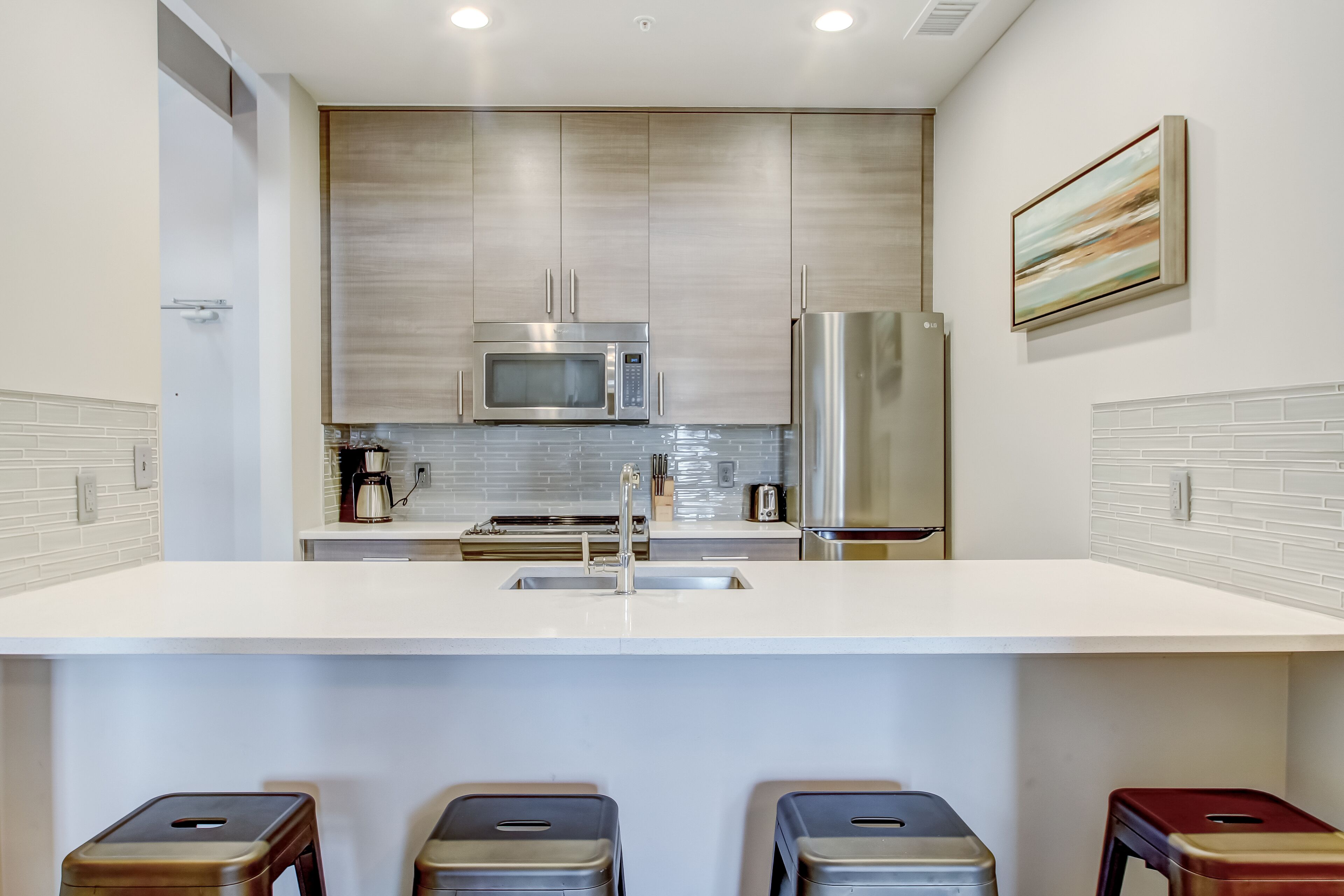 A modern kitchen with stainless steel appliances, a white countertop, and a tiled backsplash.