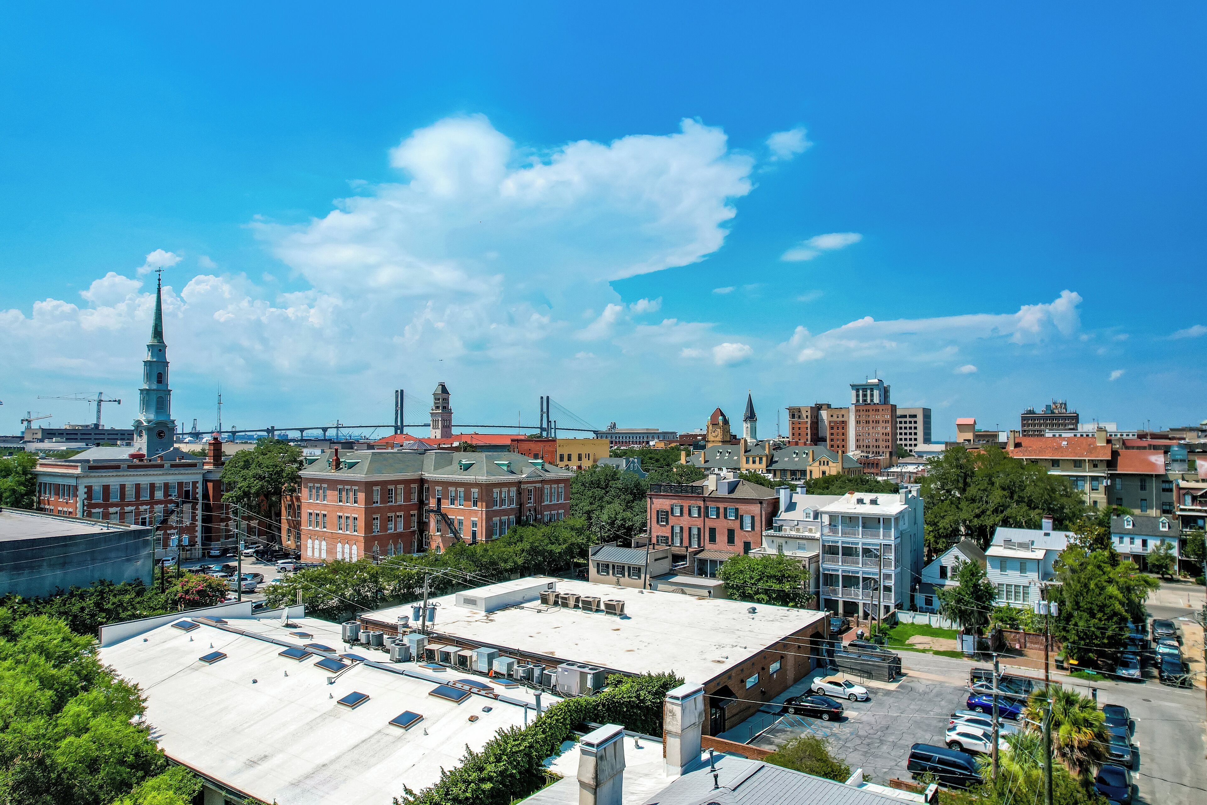 A cityscape with a mix of historic and modern buildings, a prominent church spire, and a parking area.