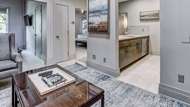 A modern interior with a living area featuring a sofa and coffee table, a kitchen with a countertop and cabinets, and a hallway with a door leading to another room. - Perfect For Large Groups, Heated Pool Access (Savannah)