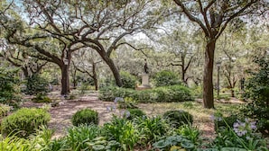 A garden with large trees, a statue, and well-maintained flower beds. - Modern Interior, Heated Pool Access (Savannah)