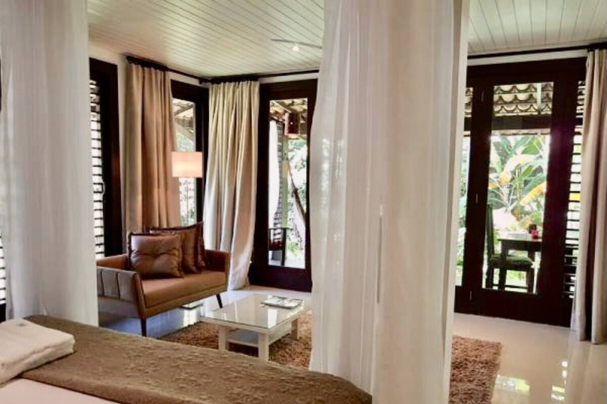 Una habitación de hotel con cama, sofá, mesa de centro y cortinas.