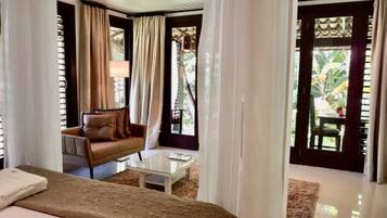 A hotel room with a bed, a sofa, a coffee table, and curtains.