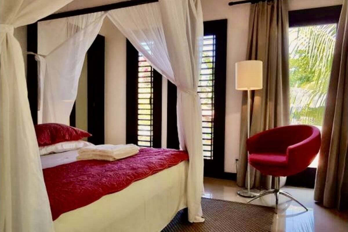 Una cama con una colcha roja y blanca, una silla roja y un dosel.