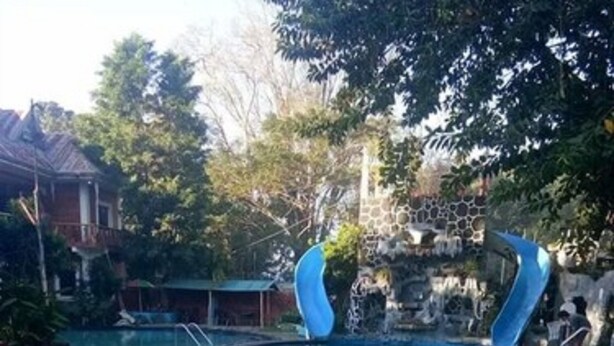 En swimmingpool med en blå vattenrutschkana, omgiven av ett däck med ett mönstrat golv.