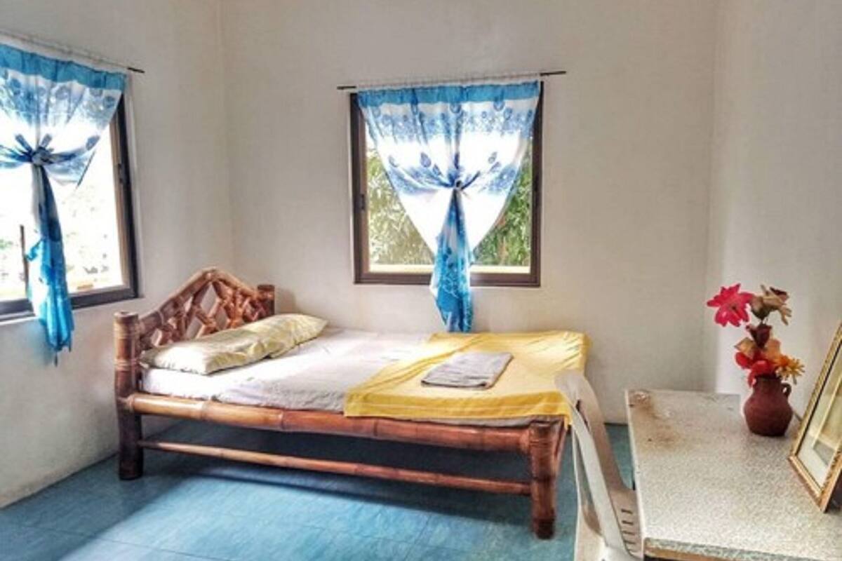 A room with a single bed, a small table, and a window with curtains.