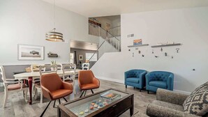 Una sala de estar moderna con comedor, una escalera y una pared decorada.