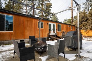 A covered patio with outdoor furniture, a fire pit, and a barbecue grill.