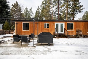 Une cabane en bois dotĂ©e dâun patio, dâun espace salon extĂ©rieur et dâun barbecue couvert.