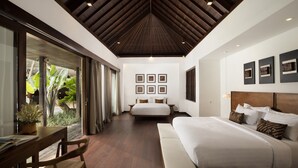 Un dormitorio amplio con una cama grande, un escritorio y vistas a un jardín a través de puertas de vidrio.