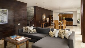 Una sala de estar moderna con una pared de acento de madera oscura, un sofá seccional gris y una mesa de centro de madera.