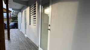 A corridor with a tiled floor, a door with a glass panel, and a window with blinds. - Perfect Location, Inside Poblado Boqueron (Boquerón)
