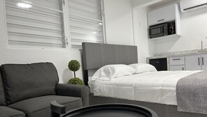 A modern hotel room with a grey sofa, a round black table, a neatly made bed, and a small potted plant. - Unique brand new apartment inside Poblado Boqueron (Boquerón)