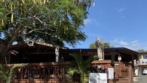 A restaurant with outdoor seating, a sign for 'Downtown Bog' by Chef Jose Carles, and a Coca-Cola sign. - Unique brand new apartment inside Poblado Boqueron (Boquerón)