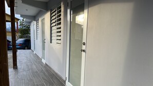 A corridor with a tiled floor, a door with a glass panel, and a window with blinds. - Unique brand new apartment inside Poblado Boqueron (Boquerón)