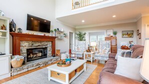 A spacious living room with a stone fireplace, comfortable seating, and a television. - Experience the Private Pond & Dock |Relax by the Fire |Raving Reviews at Blackjack Acres|Truist Park (Marietta)